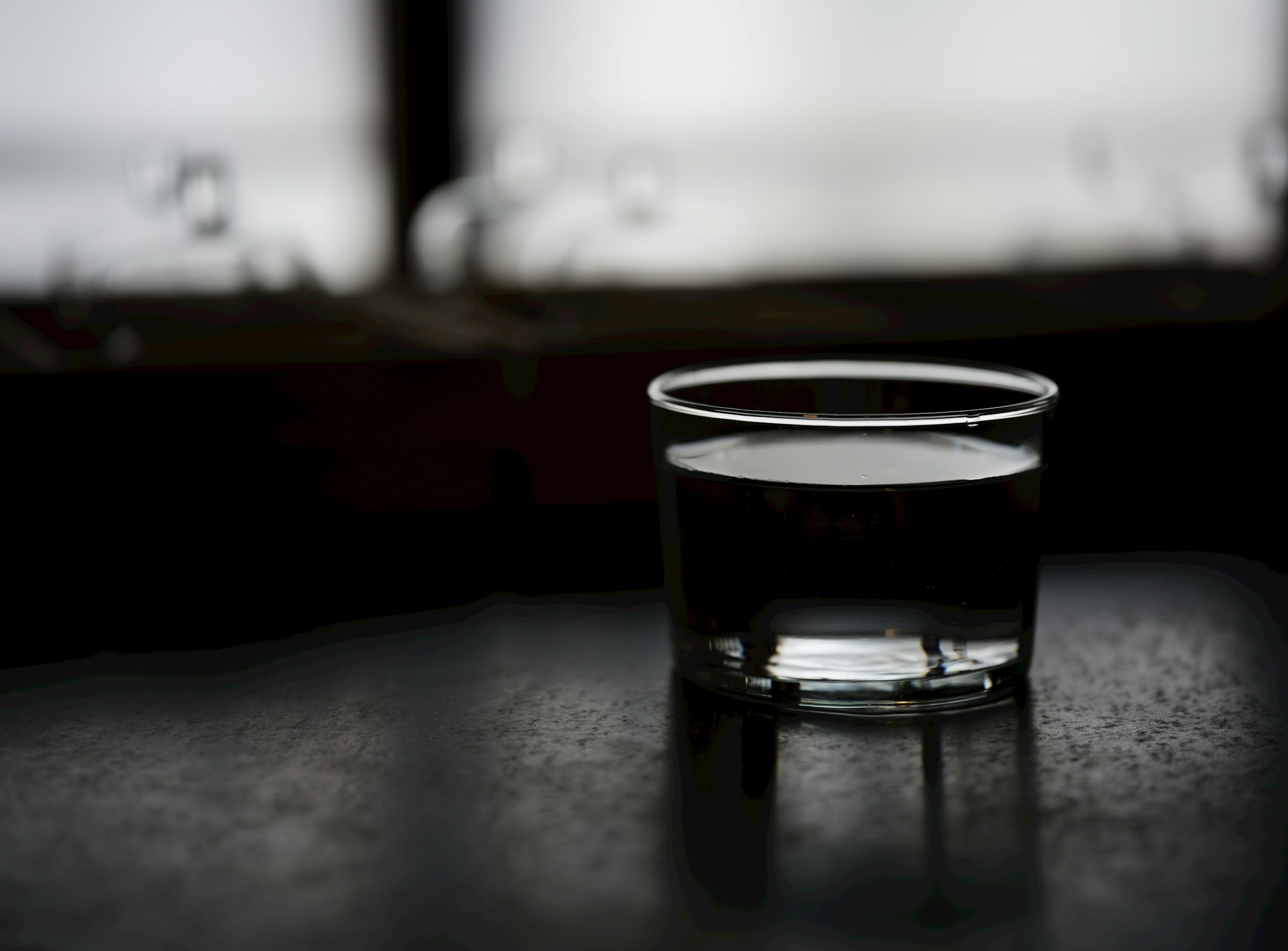 Glass of water on a dark surface, representing the clear-liquid diet before a colonoscopy on GLP-1 medication